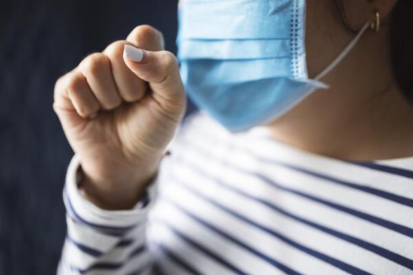 woman coughing into mask